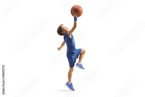Full length profile shot of a boy in a blue jersey jumping with a basketball