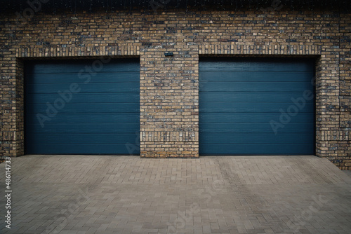 Garage Door. A double garage with blue doors at the end of a driveway