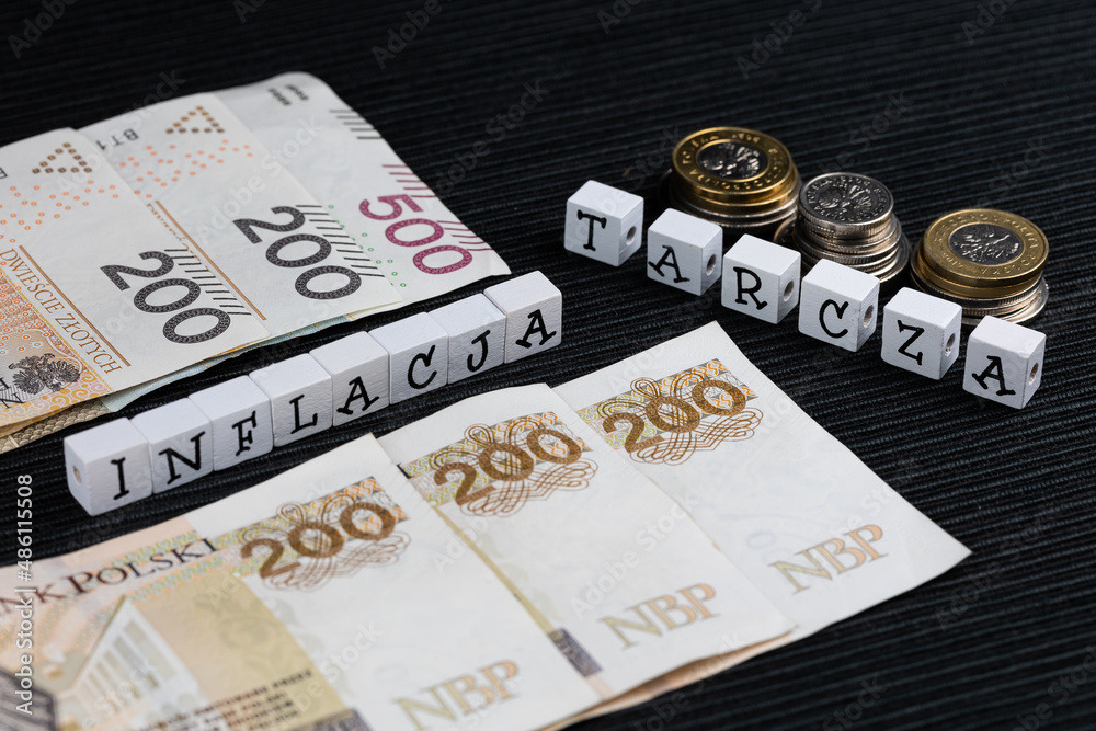 The wording "inflacja" and "tarcza"  translated as "inflation" and "shield" plus Polish coins and banknotes on the black background. High inflation eating savings Polish people. - obrazy, fototapety, plakaty 