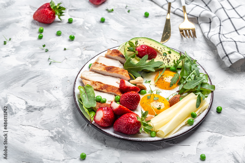 Ketogenic diet. Fried egg, avocado, strawberry, grilled chicken fillet, cheese, nuts and arugula, Low carb high fat breakfast, top view Ketogenic diet. Fried egg, avocado, strawberry, grilled chicken fillet, cheese, nuts and arugula, Low carb high fat breakfast, top view