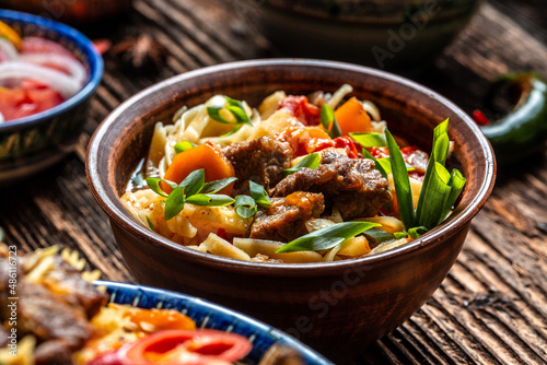 Traditional uzbek meal called pilaf. Rice with meat on plate with oriental ornament on a dark wooden background, Long banner format. space for text