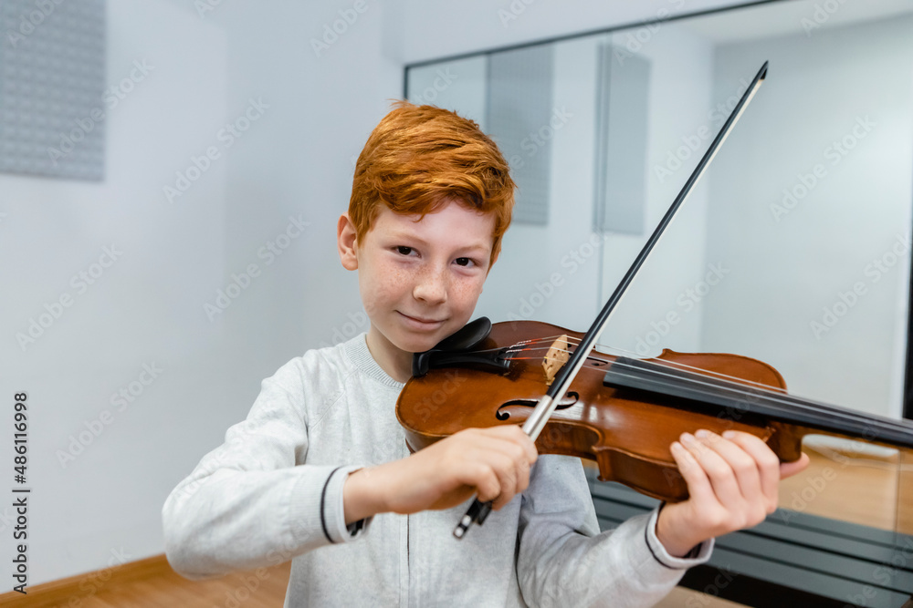 Smiling boy playing violin in music school Smiling boy playing violin in music school