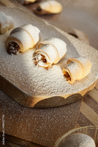 Croissants with apple jam sprinkled with powdered sugar on a wooden background.