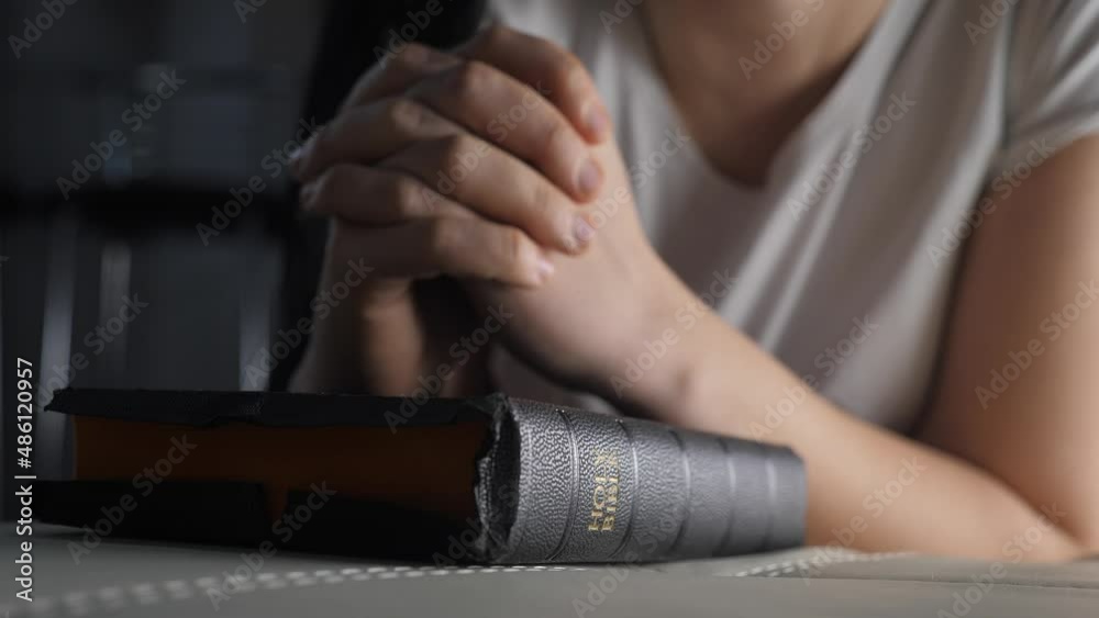 girl praying indoors at bedtime on bible. religion concept evening prayer woman brunette lifestyle hands on bible praying by bed girl praying indoors at bedtime on bible. religion concept evening prayer woman brunette lifestyle hands on bible praying by bed