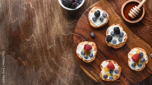 Home breakfast toasts with goat cheese and berries jam on the wooden table. Horizontal top view. Copy space