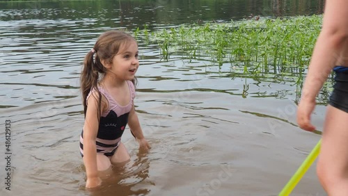 happy children, boy and girl swim in a forest lake. splashing each other. play. enjoying vacations and outdoor recreation. in blue water at sunset; bathe in lake or river and making water drops