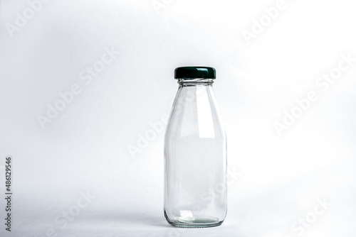 Empty glass bottle with lid on white background.