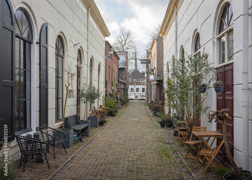 Fototapeta Naklejka Na Ścianę i Meble -  Beautiful, old, cobbled street with chairs and pot plants nearby historical centrum of dutch city of Gorinchem