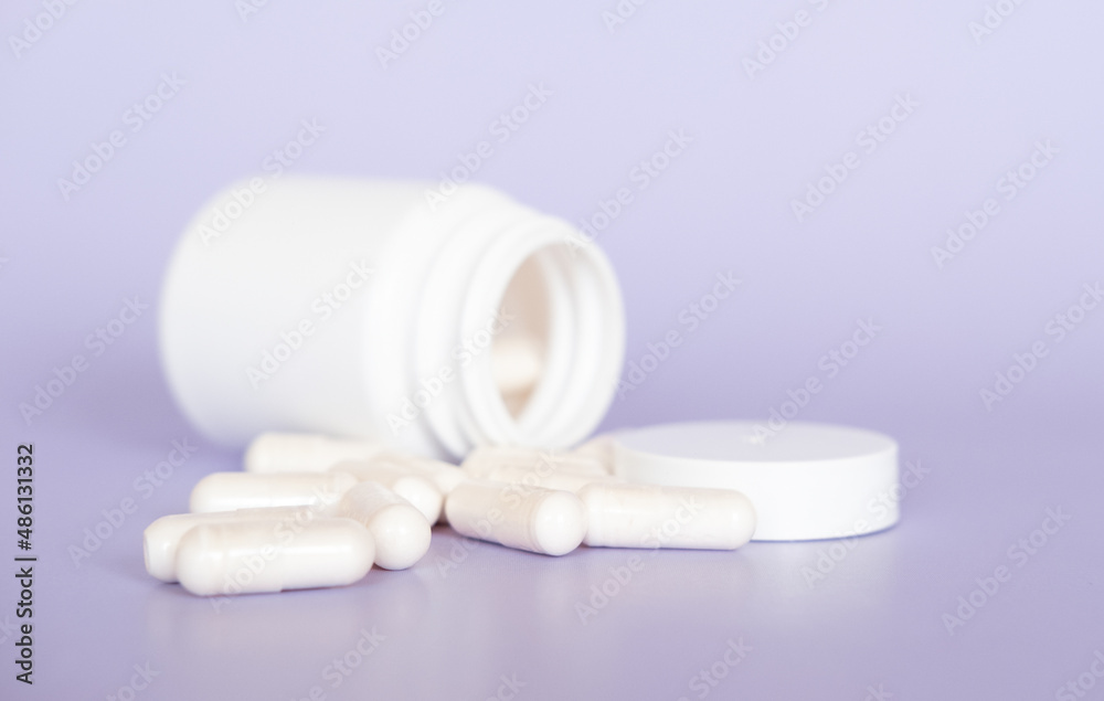 Close up white pills and capsules on purple background with copy space. Focus on foreground, soft bokeh. Pharmacy drugstore concept. Close up white pills and capsules on purple background with copy space. Focus on foreground, soft bokeh. Pharmacy drugstore concept.