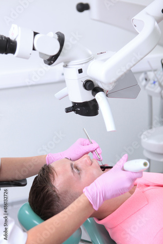 A man at a dentist s appointment. Dental examination and treatment under a microscope. Modern dentistry. Prevention of dental diseases.