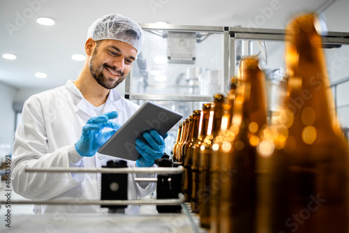Fotografija Beer bottling plant and factory worker controlling alcohol beverage production before distribution