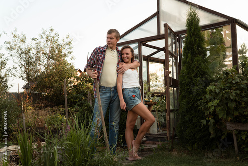 Couple in love (man and woman) staying hugging in garden close to greenhouse in countryside