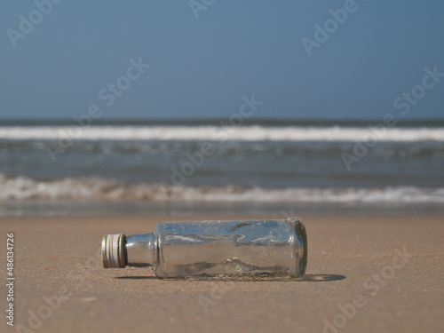 Empty bottle in the sand in front of the sea photo