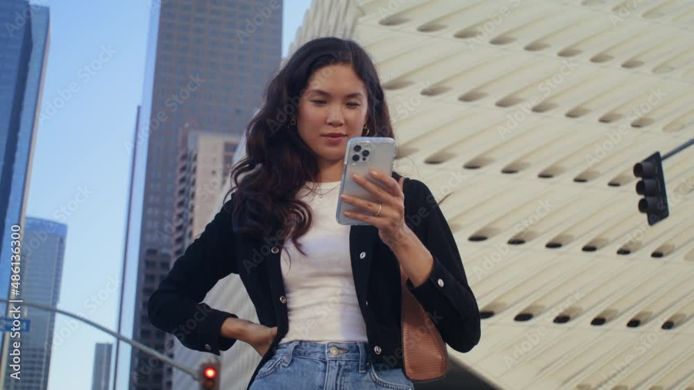 Beautiful girl using smartphone on street. Asian woman typing on phone closeup.