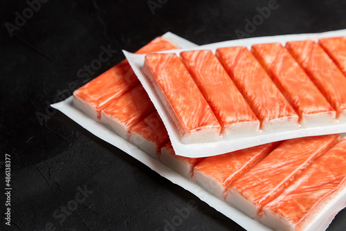 Crab sticks or imitation crab meat on black table photo