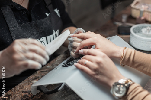 Female hands caring for nails, close-up. Woman does a manicure in a beauty salon. Professional saws a nail with a file