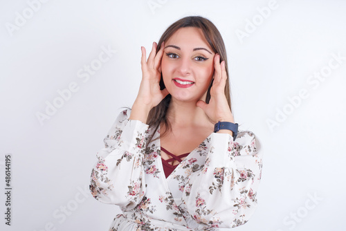 young Arab woman wearing floral dress over white background Pleasant looking cheerful, Happy reaction