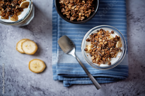 Banana Greek yogurt chocolate granola parfait in a glass