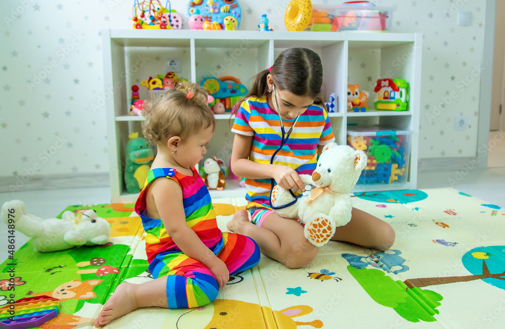 Fototapeta premium Children play together treat the bear. Selective focus.