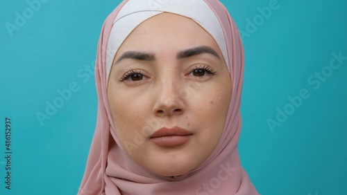 Extreme close up portrait of Young middle eastern Muslim woman in hijab looking serious at camera. Traditional Islamic culture and religion concept. Arabian religious woman. Stduio shot photo