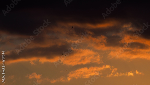 Crépuscule orangé, sous un ciel partiellement couvert