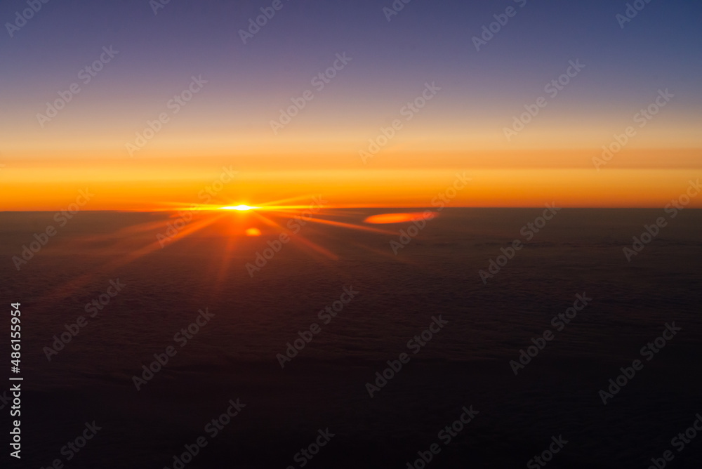 Sunrise from the window of the plane. The horizon is colored by the orange light of the sun. The first rays of the rising sun.