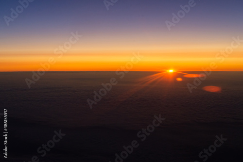 Sunrise from the window of the plane. The horizon is colored by the orange light of the sun. The first rays of the rising sun. © Михаил Шаповалов