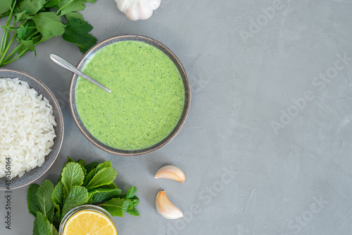 Healthy fresh green chutney sauce. With fresh mint pudina and yogurt. Spicy indian cuisine. Served with rice, lemon, garlic and parsley. Top view, grey background, copy space