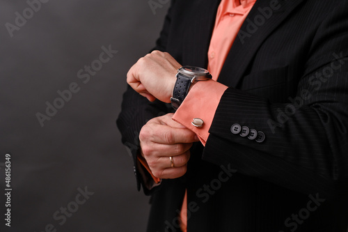 the man checks the time on his wristwatch. a businessman in a suit looks at his watch.