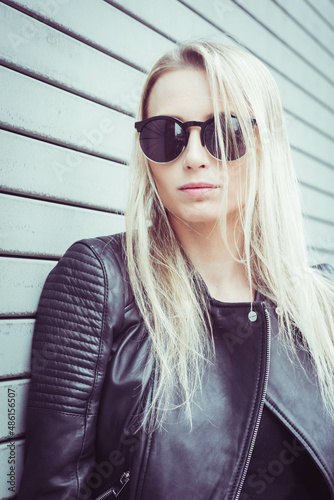 Outdoor portrait of caucasian blond girl in black leather outfit
