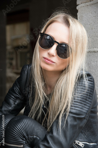 Outdoor portrait of caucasian blond girl in black leather outfit