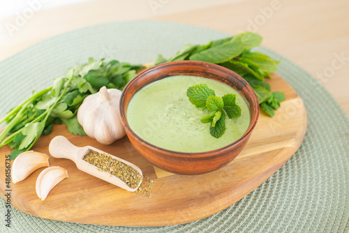 Healthy fresh green chutney sauce. With fresh mint pudina and yogurt. Spicy indian cuisine. Served on brown bowl with spices, garlic and parsley on wood board, light background