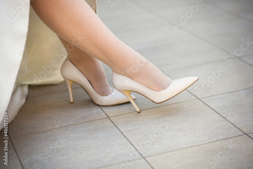 Nice bride's legs in ivory wedding high heeled shoes