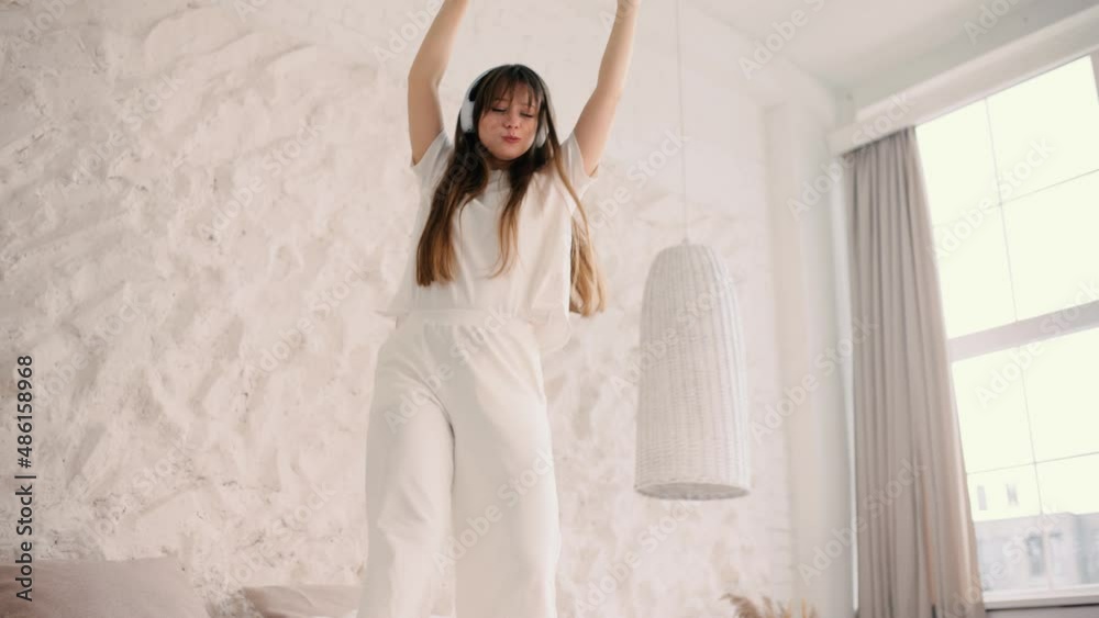 Funny happy young woman in headphones dancing on a bed and eating pizza. Funny moving celebrate day off. High quality 4k footage Funny happy young woman in headphones dancing on a bed and eating pizza. Funny moving celebrate day off. High quality 4k footage