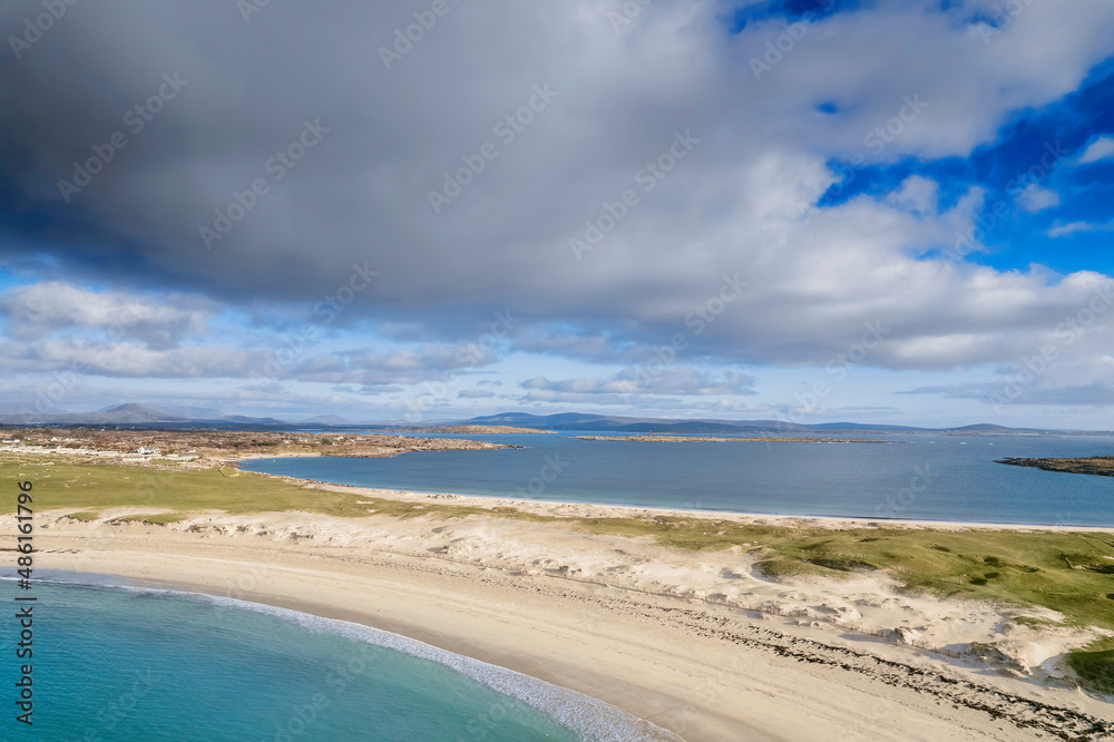 Turquoise color ocean water and warm sandy Dog's bay beach and Gurteen bay in the background. County Galway, Ireland. Irish landscape. Popular tourist area with amazing nature scenery.