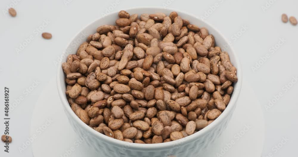 beans falling into white bowl on white background beans falling into white bowl on white background