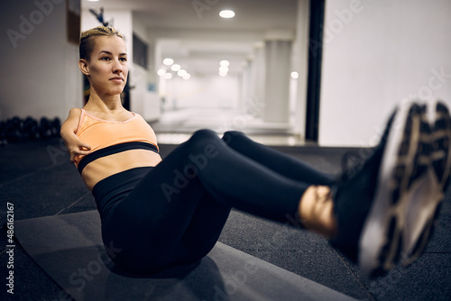 Athletic woman with a disability doing sit-ups while exercising at gym.