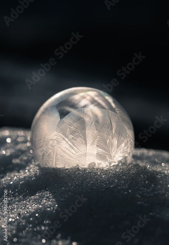 Close up of frozen soap bubble outdoors in the snow on a cold day.