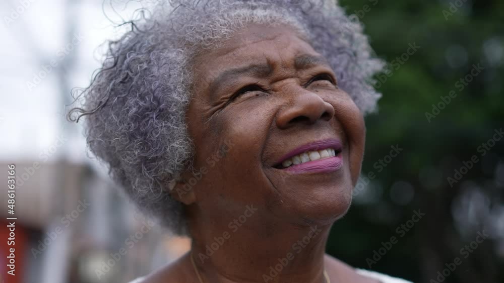 A hopeful senior woman portrait smiling outside looking at sky
