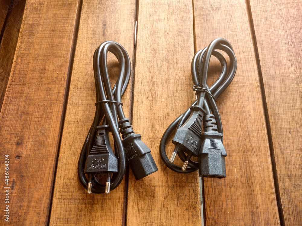 Power supply cables, with black with connector, on a wooden background. 
