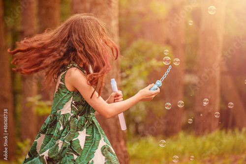 Happiness, summer. Happy girl with soap bubbles back to the camera.