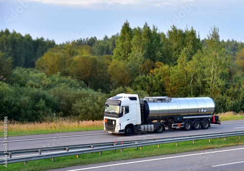Isothermal Tank truck driving on highway. Oil and Gas Transportation and Logistics. Metal chrome cistern tanker with petrochemicals products. Liquid Chemical Freight. Out of focus.