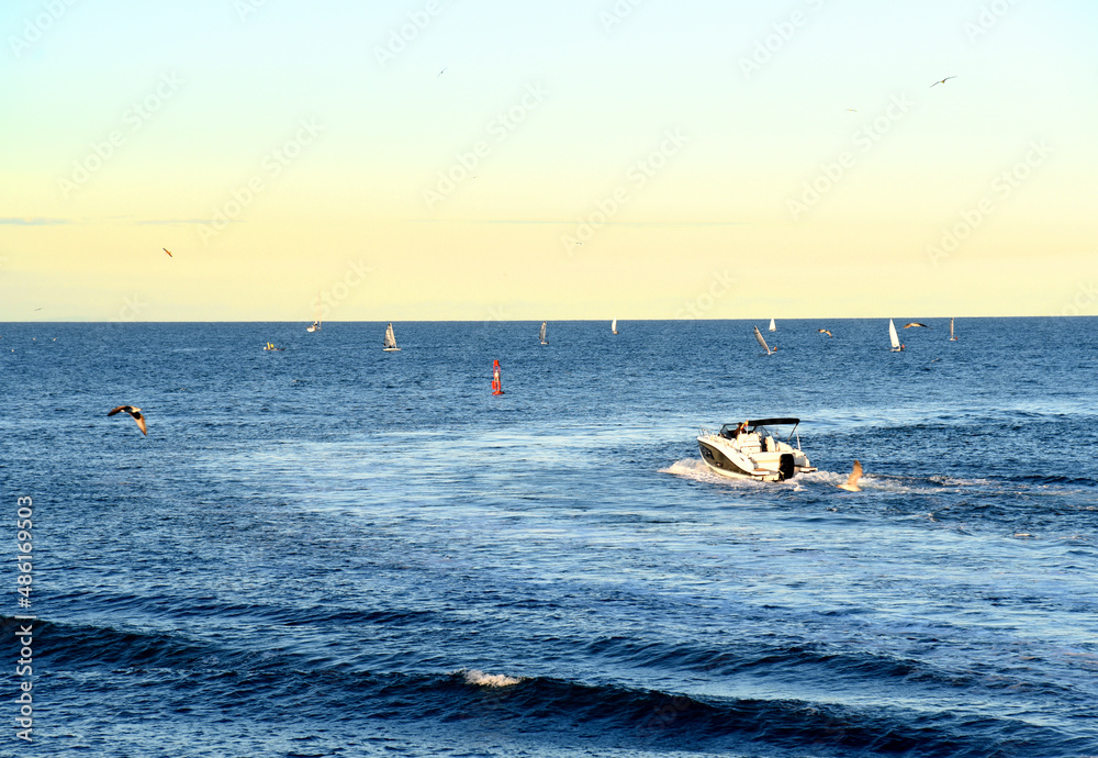 Motor boat in the sea at sunset. Yacht and motorboat on waves in Mediterranean Sea. Skiff and Sailboat in ocean. Yachting and sailing sport. Speedboat or powerboat on the waves near the Spanish coast.