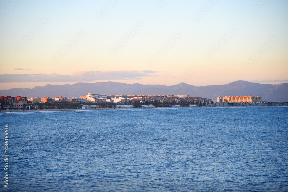 View on coastline and beach from La Marina de Valencia on the sea to the Las Arenas beach, Playa de las Arenas, Platja del Cabanyal and Playa de la Malvarrosa. Waves at sea on sunset.