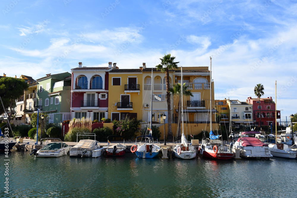 Yachts and motor boats in marina Port Saplaya, Valencia, Alboraya, Spain. Luxury yacht and fishing motorboat in yacht club on background of the colourful houses at Mediterranean Sea. Sailboat port.