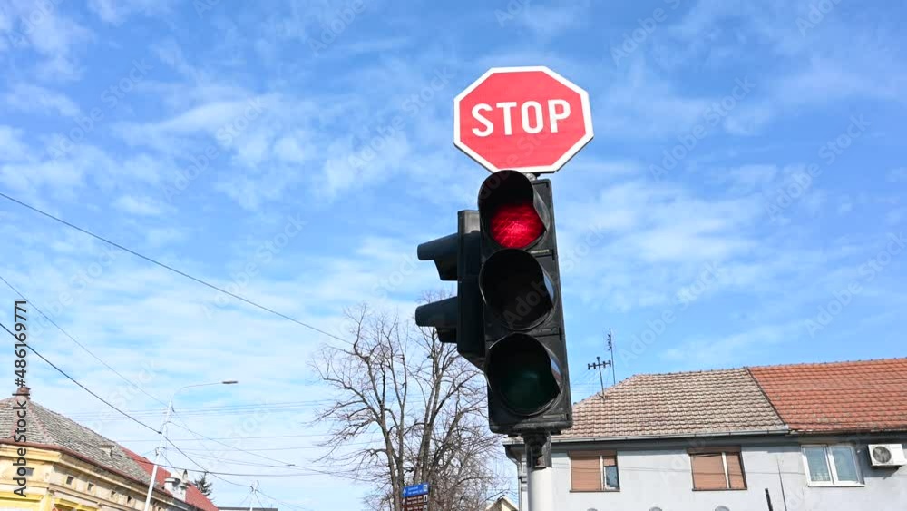 Stop sign and traffic light at an intersection. Traffic signals. Red, yellow and green lights. Red stop sign on the road. Traffic sign along a city street.