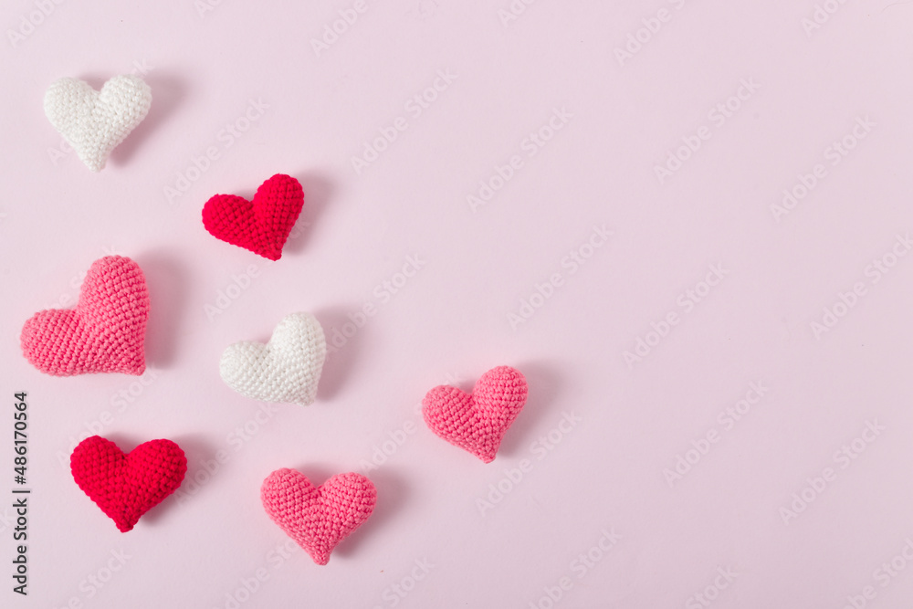 Background with pink knitted hearts for a festive Valentine's Day. Banner for February 14. Greeting card with hearts. Space for copying. Flat position, top view