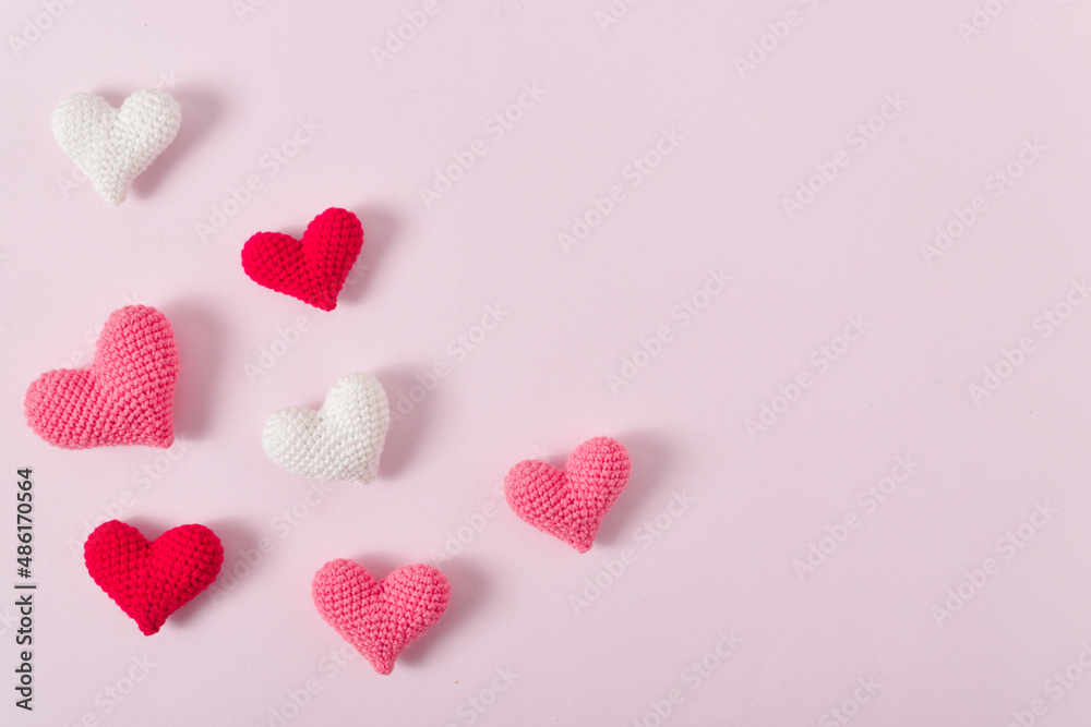 Obraz premium Background with pink knitted hearts for a festive Valentine's Day. Banner for February 14. Greeting card with hearts. Space for copying. Flat position, top view