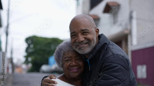 An adult son embracing elderly mother family love affection outside