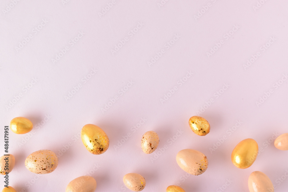 Various Easter eggs of yellow shades lie on a pink background. Easter background with painted eggs and sequins. Copy space. Flat lay, top view. Various Easter eggs of yellow shades lie on a pink background. Easter background with painted eggs and sequins. Copy space. Flat lay, top view.
